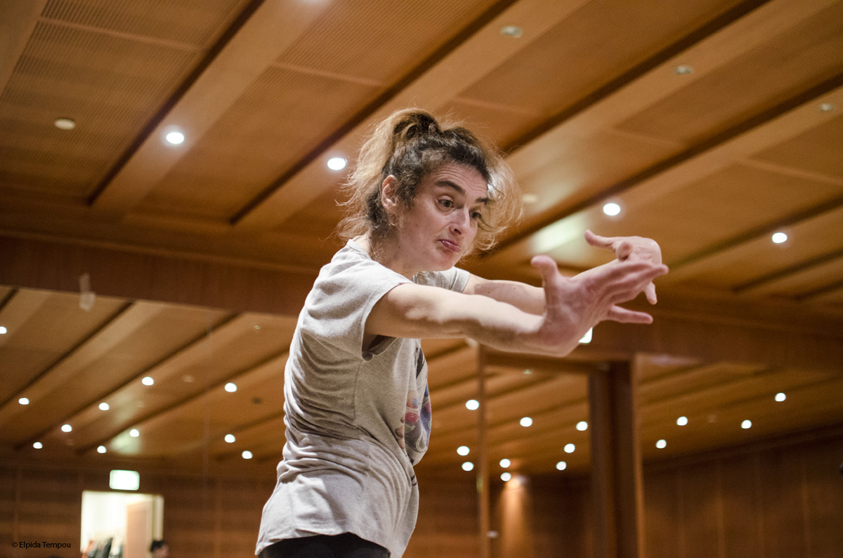 a dancer looks at the camera with her arms expressively reaching in front