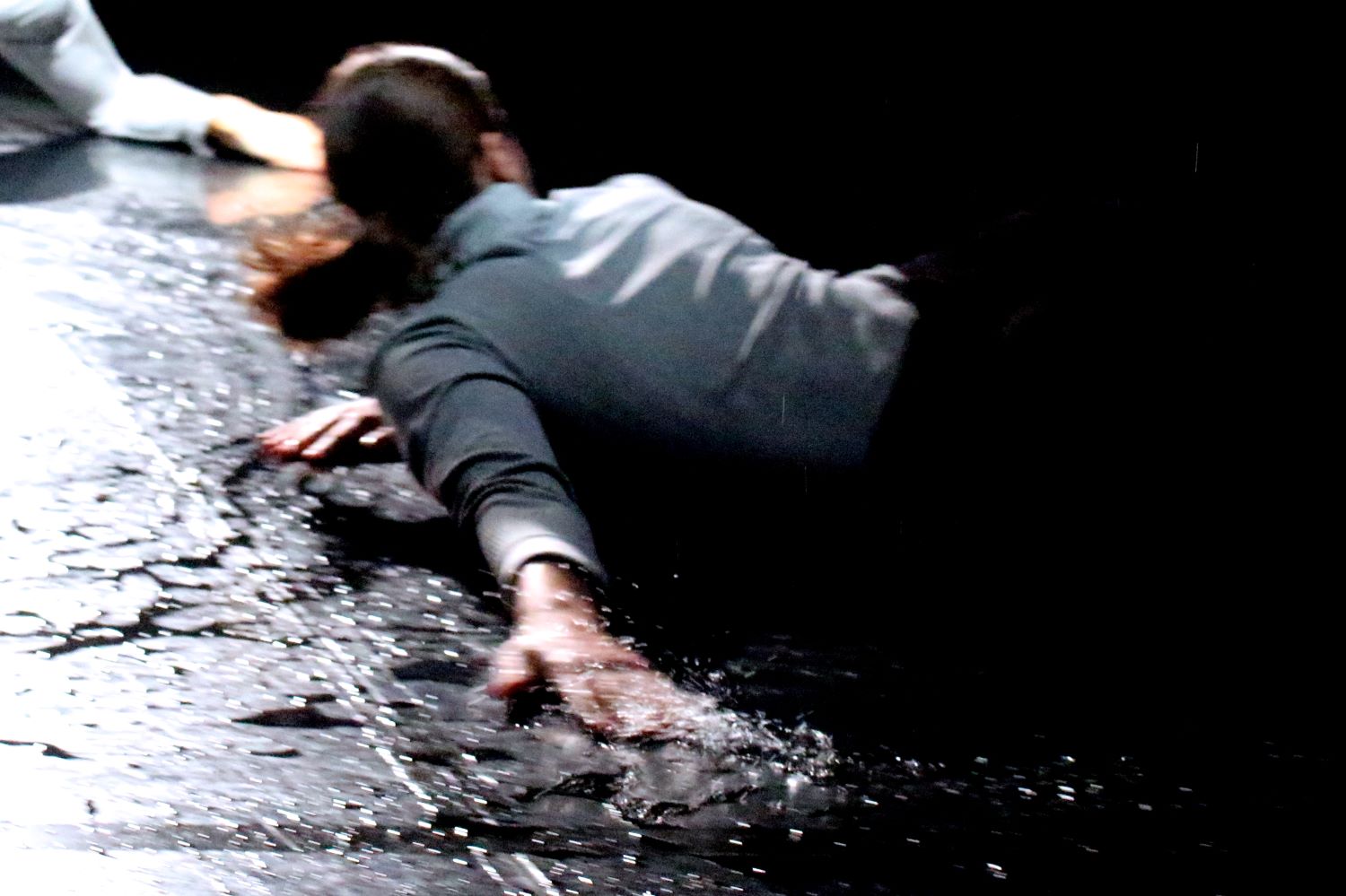 A woman is sliding with her left hand and torso on a wet floor