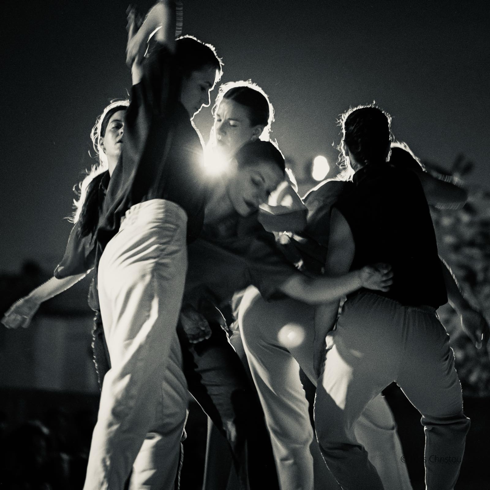 Seven dancers in a close formation passing through one another