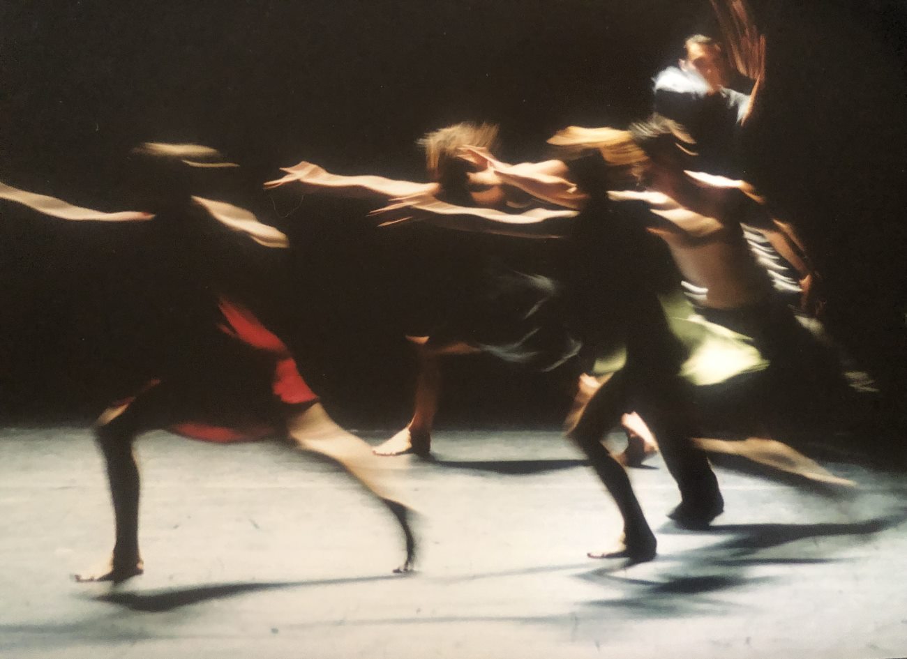 Four performers are extending their right hand forward in a quick motion while a fifth one is behind on the right hand side