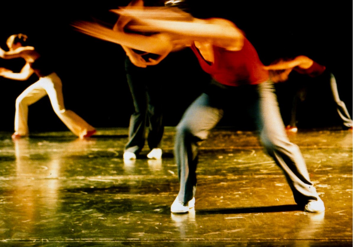 A performer is seen frontstage with two legs apart throwing her arms to her right hand side