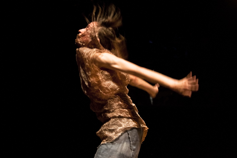 a performer is seen profile with her arms extended dynamically backwards 