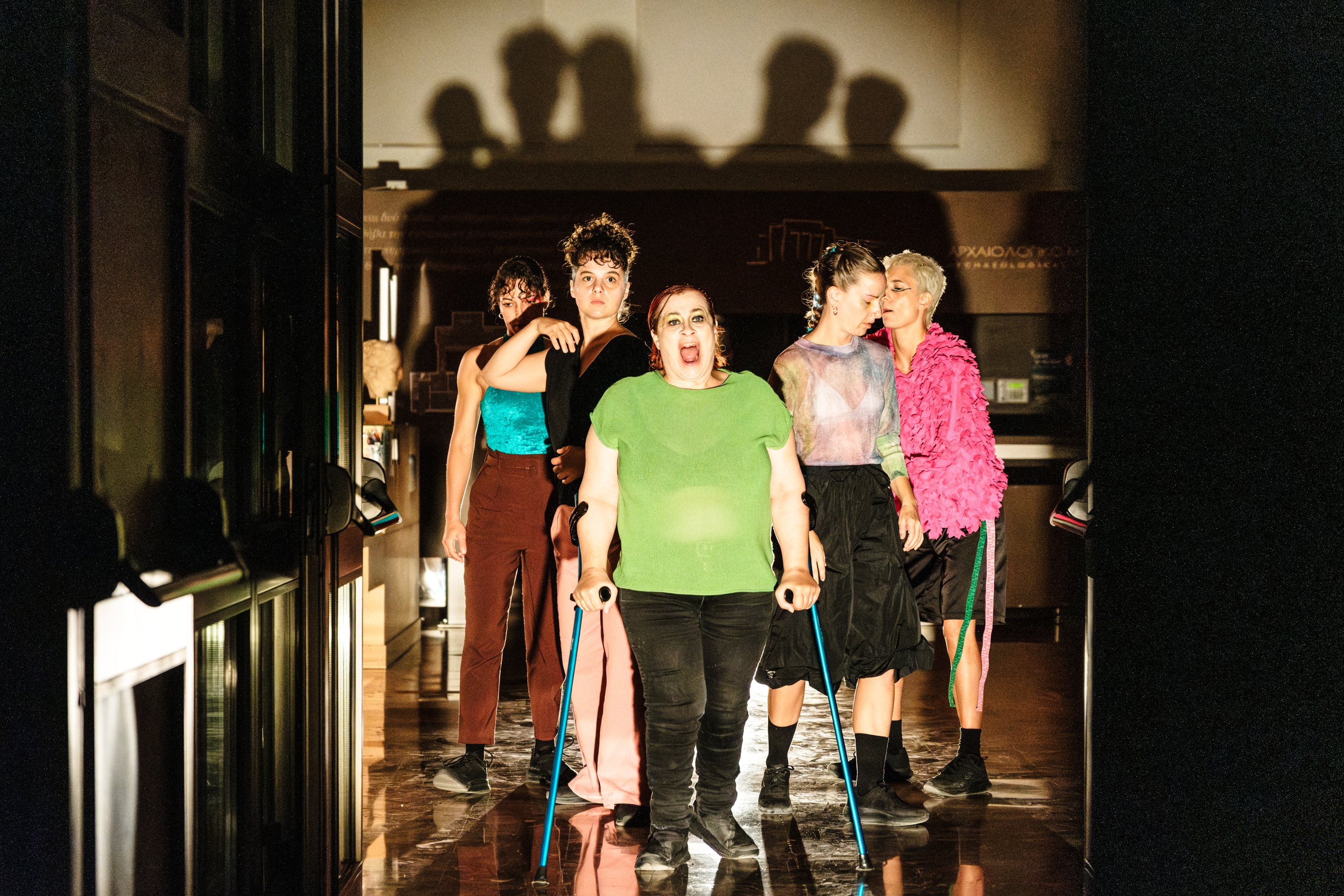 Five women dressed in vibrant colours walk toward us. Leading the walk is Demy, a crip female dancer who is using her crutches. 