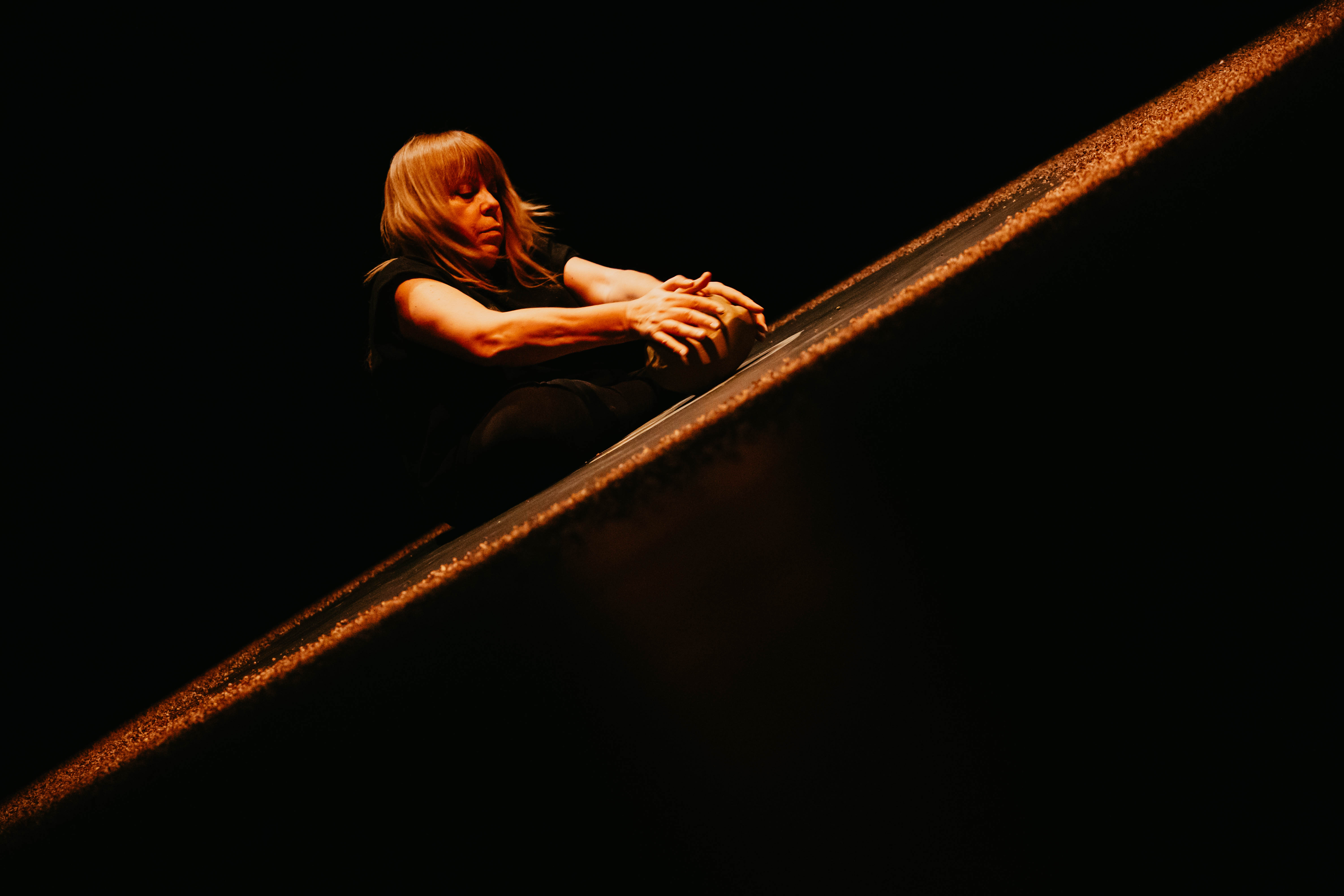 Η Βιβή καθισμένη με τα χερια απλωμένα μπροστά της κρατάει ένα κομμάτι πηλού