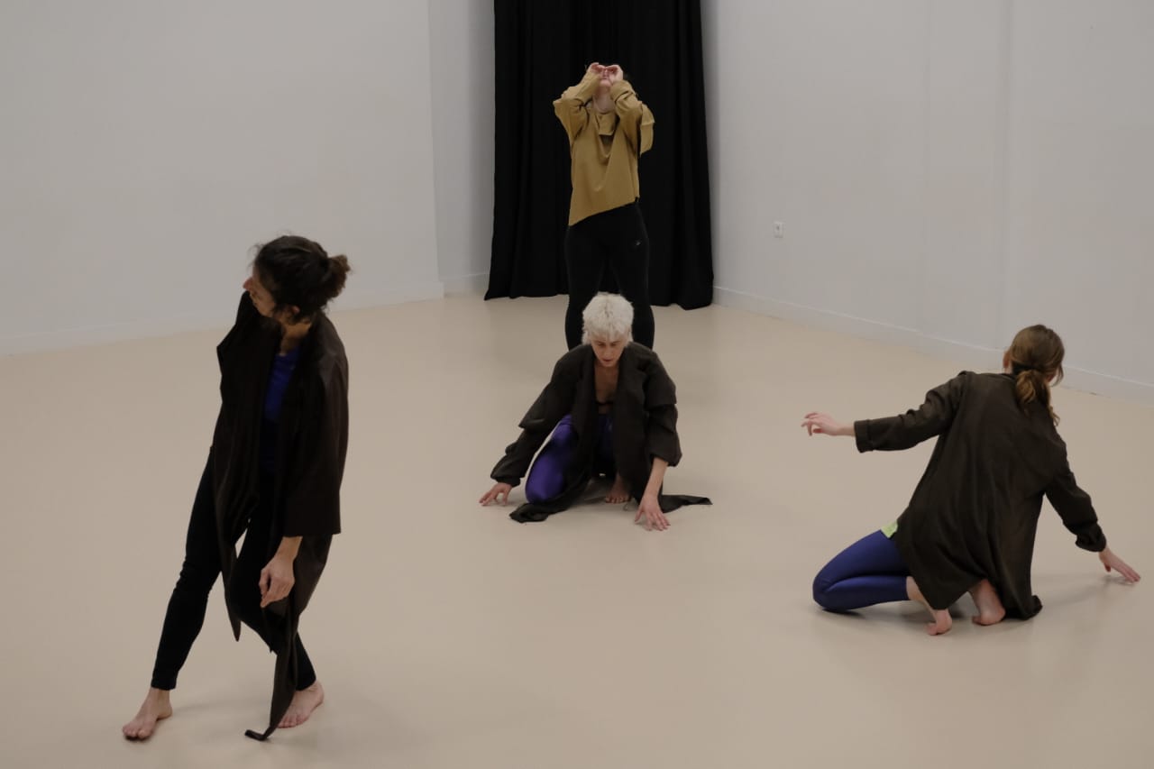 Against a stark black and warm beige backdrop, the quartet forms a landscape of shifting bodies