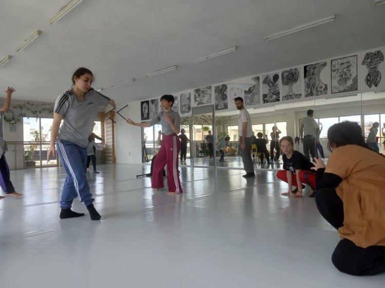 a group of performers  with and without disability moving in a white dance studio space