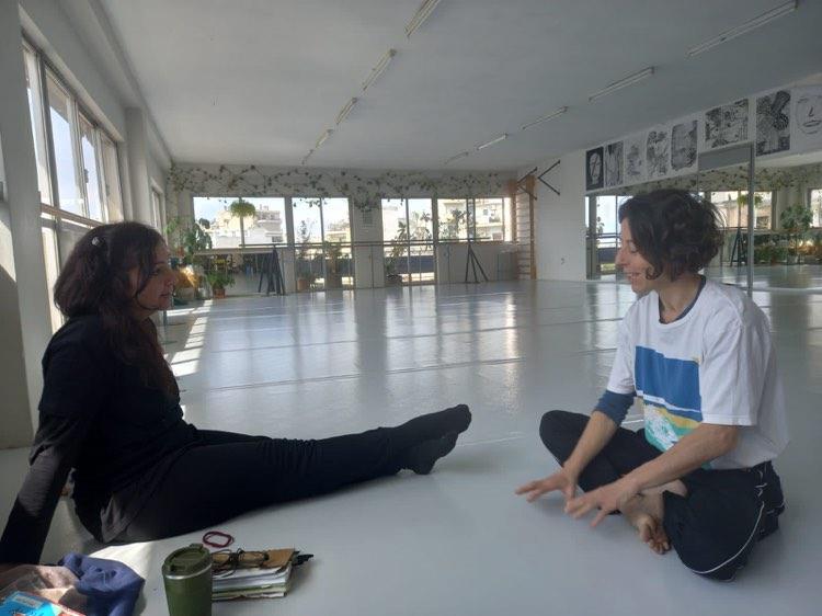 Maria and Monia sitting opposite one another in a white studio space