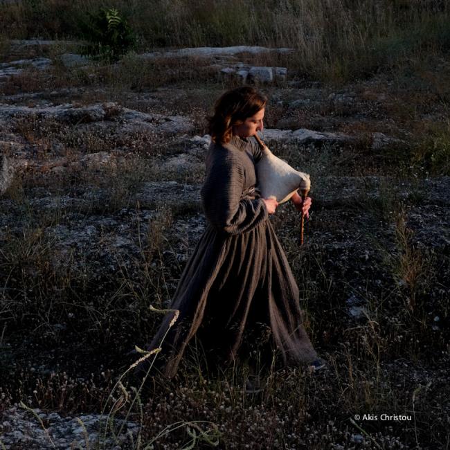 A women performer, Ioanna, is seen playing the gaida