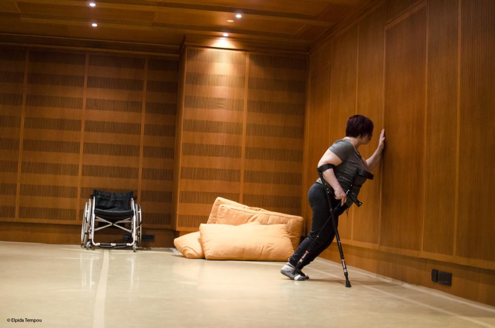 a crip dancer leans against the wall holding one of her crutches