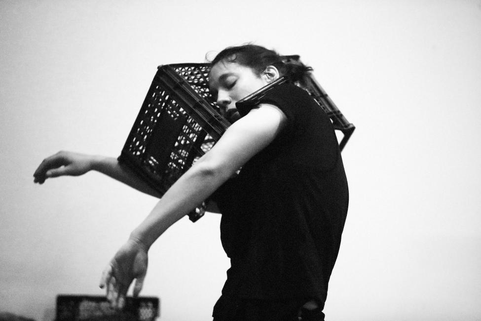 a female dancer hugs a crate with her right arm and head