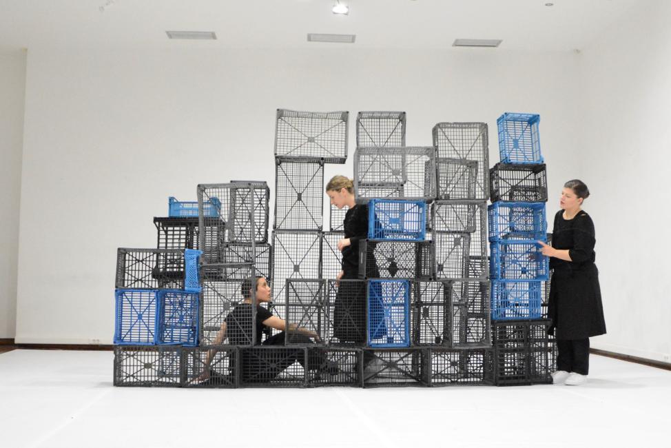 a Terrain of three dancers in a landscape of vertically put crates
